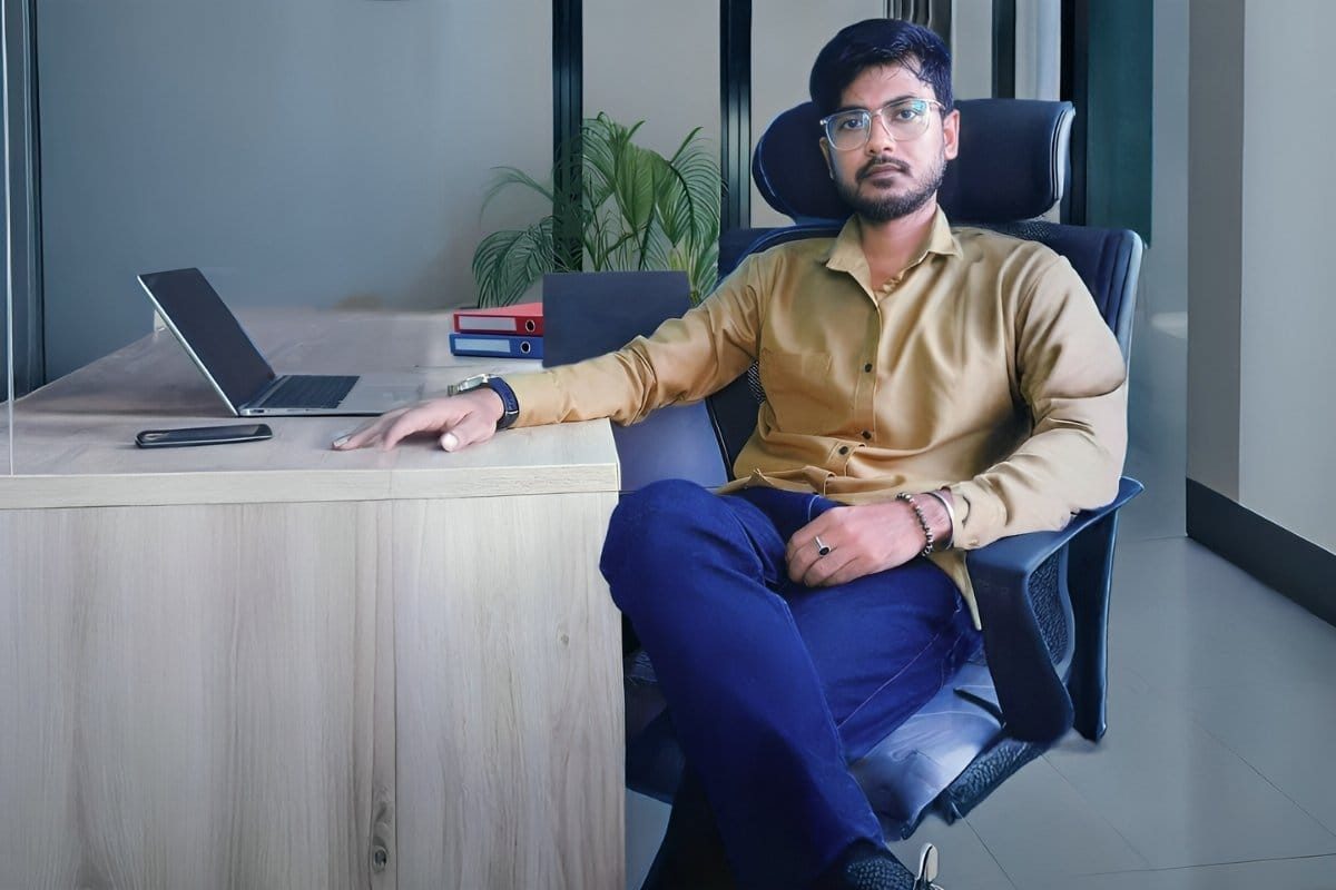 Mukesh Kumar Jena sitting confidently at a desk with a laptop, wearing a formal suit — professional portrait for Jena Digital Solutions website.